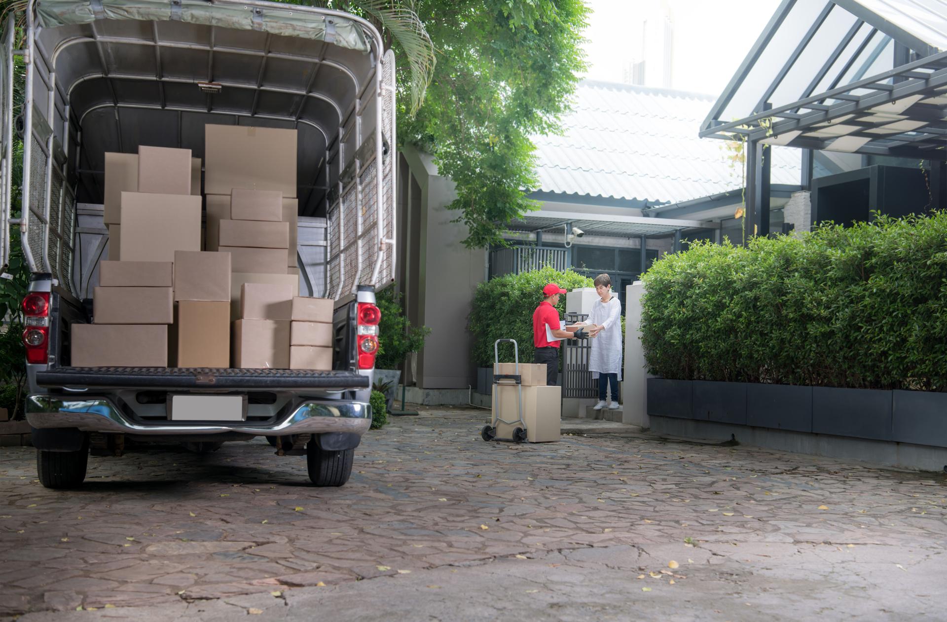 Asian delivery man in red uniform delivering parcel boxes to woman recipient at home